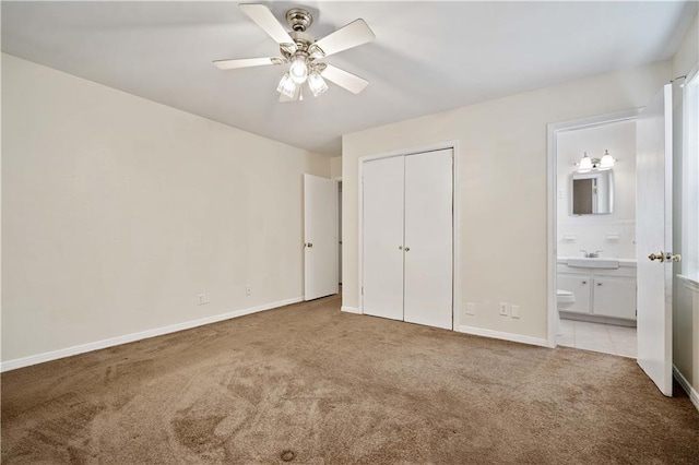 unfurnished bedroom with ceiling fan, a closet, light carpet, and ensuite bath