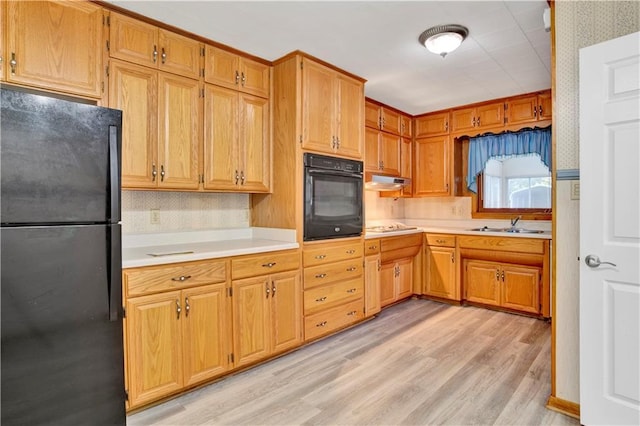 kitchen with black appliances, light wood-type flooring, and sink