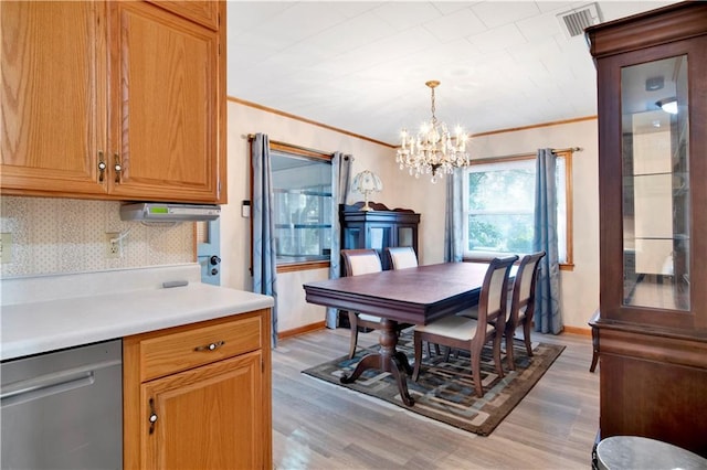 dining area featuring an inviting chandelier, ornamental molding, and light hardwood / wood-style flooring