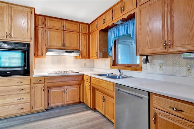 kitchen featuring black oven, tasteful backsplash, sink, stainless steel dishwasher, and light hardwood / wood-style flooring