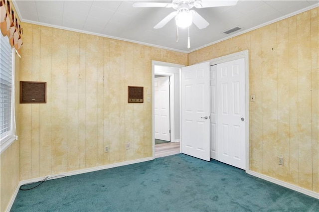 unfurnished bedroom with ceiling fan, wooden walls, dark carpet, and ornamental molding