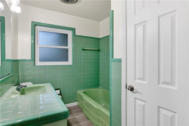 bathroom featuring hardwood / wood-style floors, vanity, tile walls, and bathing tub / shower combination