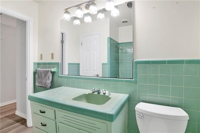 bathroom with tile walls, toilet, vanity, and walk in shower