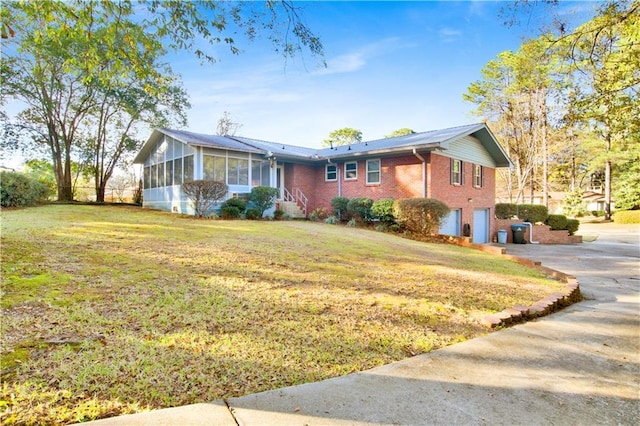 single story home featuring a front yard, a garage, and a sunroom