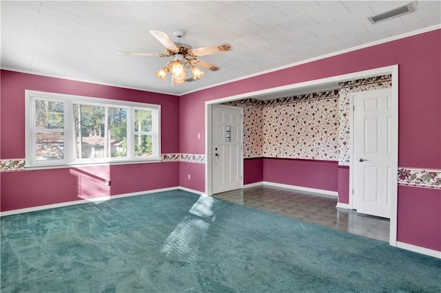 empty room with ceiling fan, crown molding, and dark colored carpet