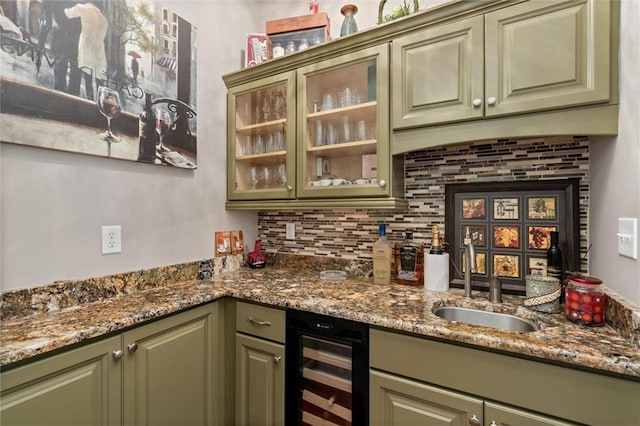 bar with dark stone counters, green cabinets, sink, wine cooler, and tasteful backsplash