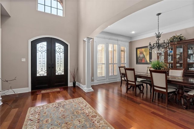 foyer featuring dark wood-type flooring, french doors, a healthy amount of sunlight, and a notable chandelier