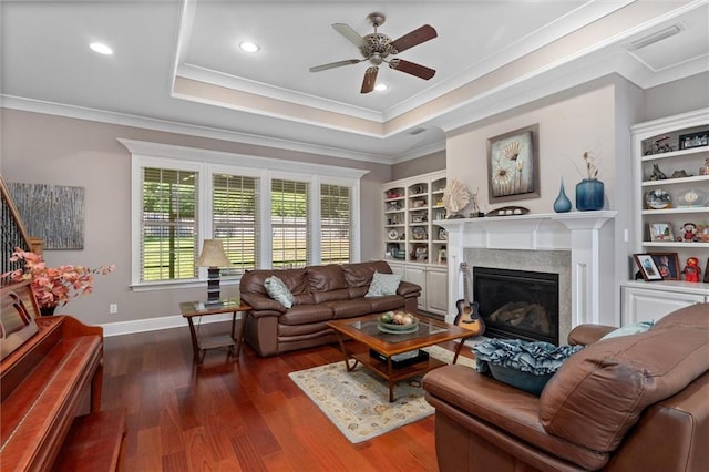 living room with dark hardwood / wood-style flooring, a raised ceiling, ceiling fan, and ornamental molding