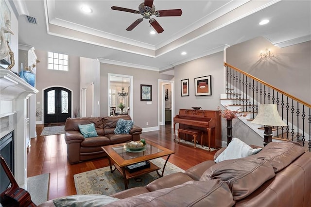 living room with a high end fireplace, hardwood / wood-style floors, a tray ceiling, and crown molding