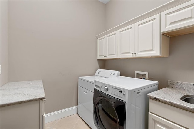 clothes washing area with cabinets, sink, light tile patterned flooring, and washing machine and clothes dryer