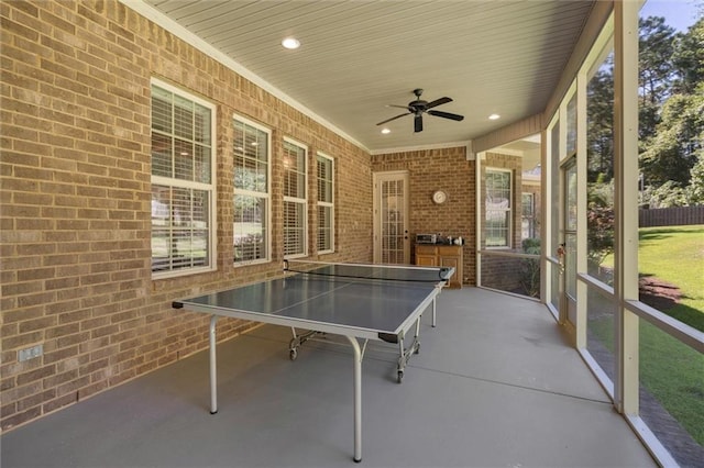 playroom featuring ceiling fan and brick wall