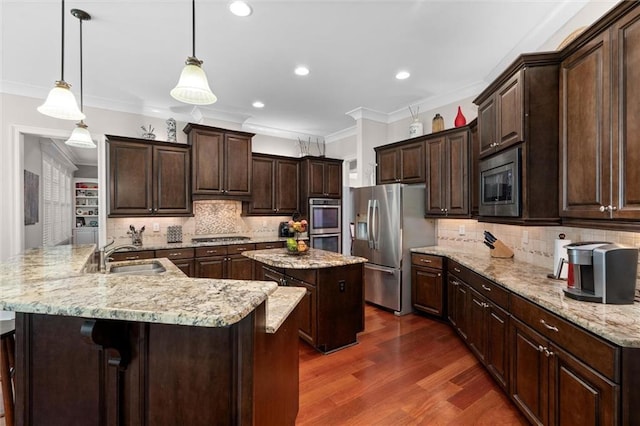 kitchen featuring sink, hanging light fixtures, crown molding, appliances with stainless steel finishes, and a large island