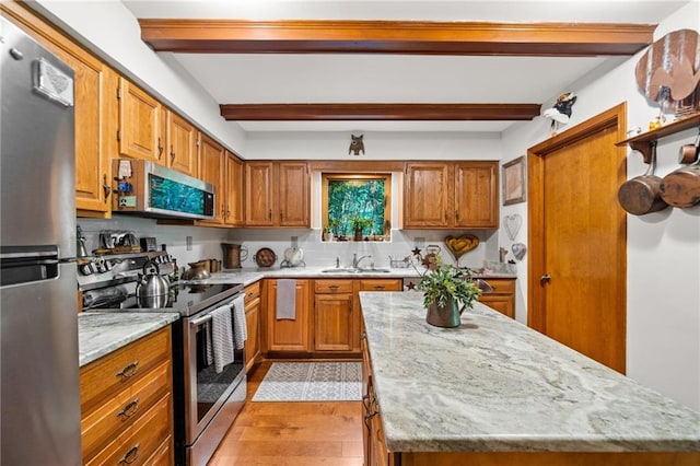 kitchen featuring stainless steel appliances, light hardwood / wood-style floors, sink, beamed ceiling, and light stone countertops