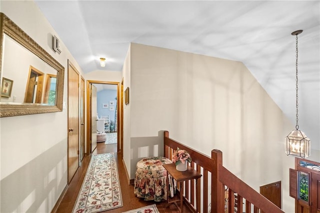 hallway with a notable chandelier, vaulted ceiling, and hardwood / wood-style floors