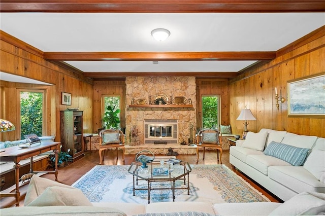 living room with beam ceiling, wood walls, a stone fireplace, and wood-type flooring