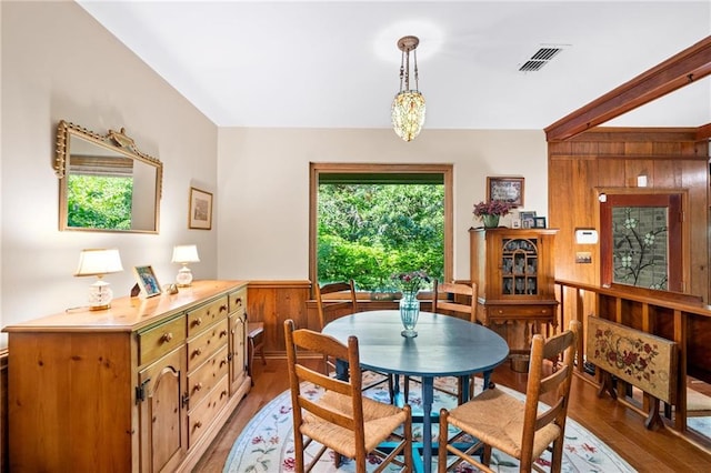 dining room with hardwood / wood-style flooring and wood walls