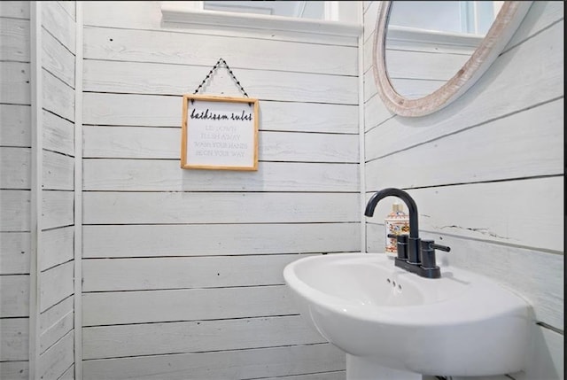 bathroom with wood walls and sink