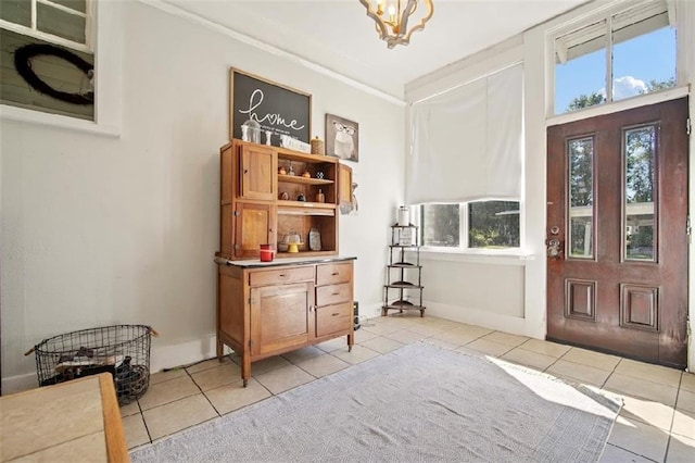 tiled entryway featuring an inviting chandelier and crown molding