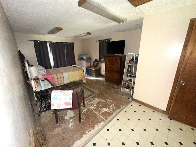 bedroom featuring a textured ceiling, baseboards, and tile patterned floors