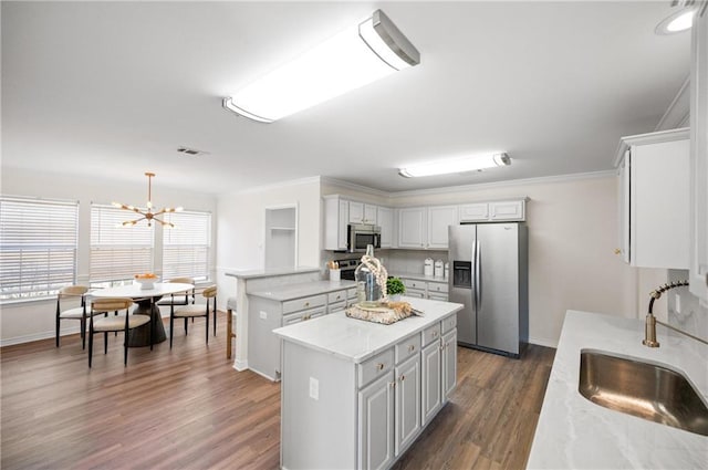 kitchen with pendant lighting, sink, white cabinets, a center island, and stainless steel appliances