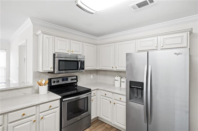 kitchen with tasteful backsplash, stainless steel appliances, crown molding, and white cabinets