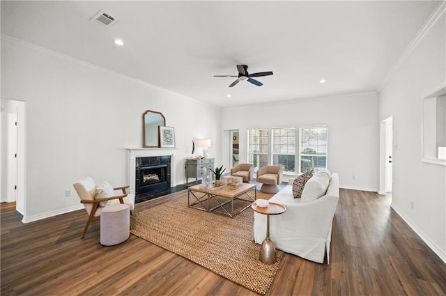 living room with dark wood-type flooring, ceiling fan, ornamental molding, and a fireplace