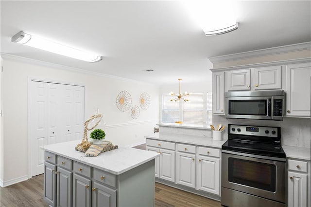 kitchen with dark wood-type flooring, ornamental molding, a center island, and appliances with stainless steel finishes