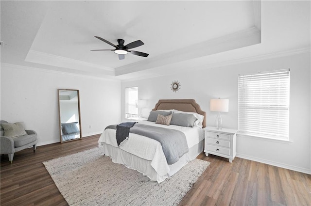 bedroom featuring a raised ceiling, ornamental molding, dark hardwood / wood-style floors, and ceiling fan