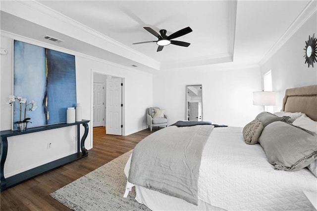 bedroom featuring crown molding, dark wood-type flooring, ceiling fan, and a tray ceiling