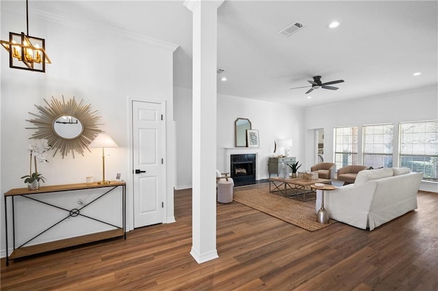 living room featuring a premium fireplace, ornamental molding, decorative columns, and dark hardwood / wood-style flooring