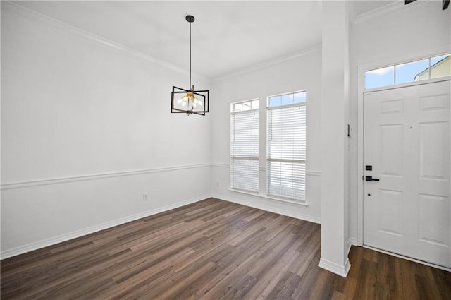 entryway featuring dark wood-type flooring, ornamental molding, and an inviting chandelier