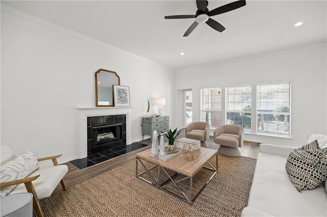 living room with crown molding, ceiling fan, dark hardwood / wood-style flooring, and a tile fireplace