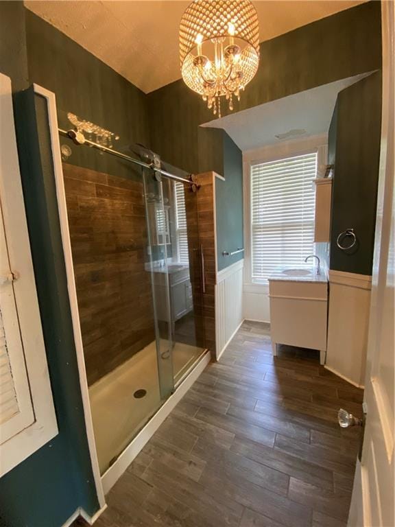 112 Kilmarnock St, Mobile, AL 36604 - bathroom featuring a stall shower, wood finished floors, a chandelier, wainscoting, and a sink