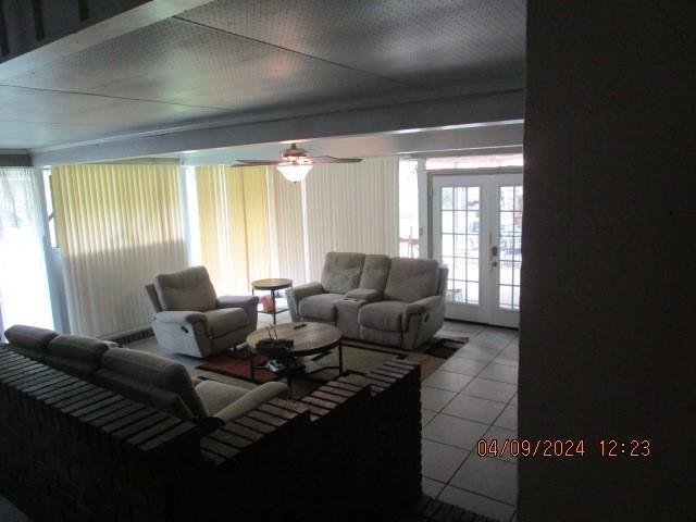 tiled living room with french doors and ceiling fan