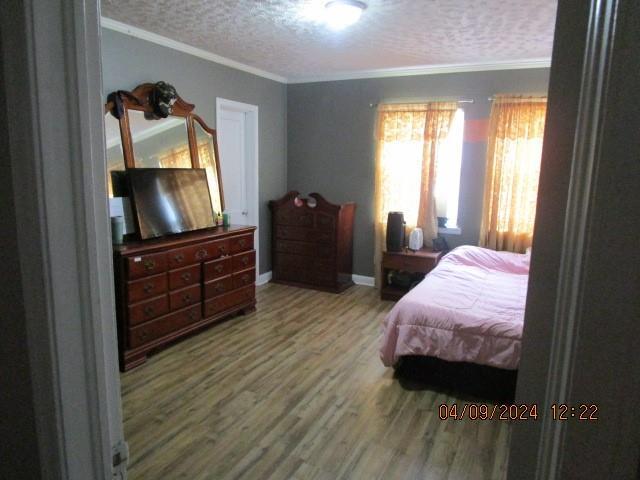 bedroom with a textured ceiling, hardwood / wood-style flooring, and crown molding