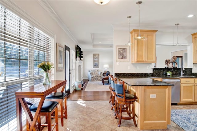 kitchen featuring light brown cabinetry, stainless steel dishwasher, sink, a raised ceiling, and pendant lighting