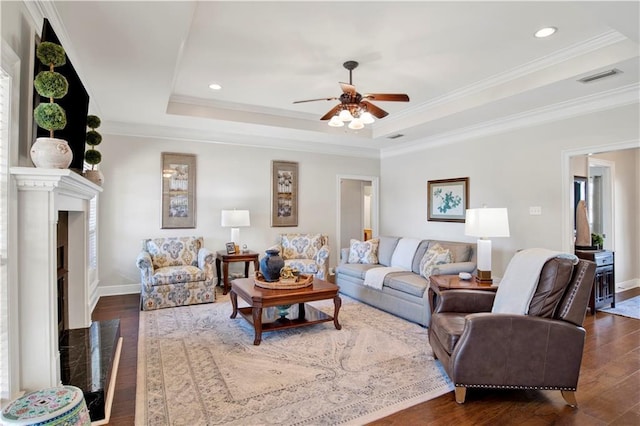 living room featuring crown molding, dark wood-type flooring, ceiling fan, and a raised ceiling