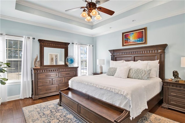 bedroom with ceiling fan, a tray ceiling, dark hardwood / wood-style flooring, and crown molding