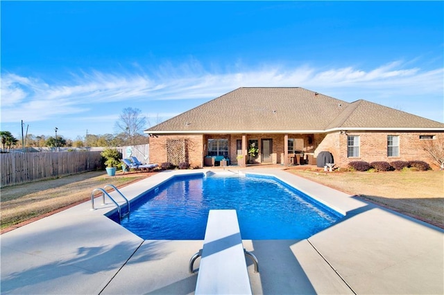 view of swimming pool with a diving board and a patio area