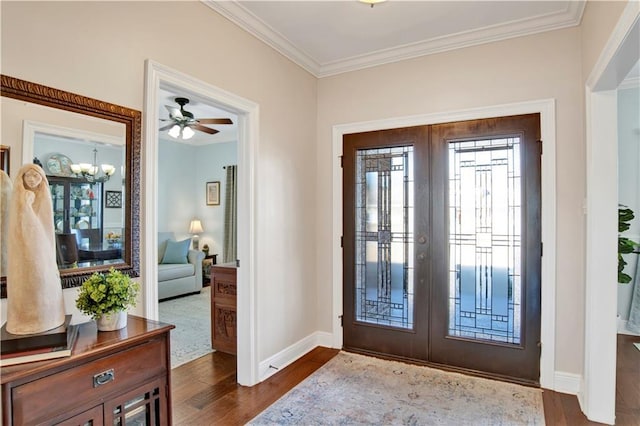 foyer with crown molding, dark hardwood / wood-style flooring, a chandelier, and french doors