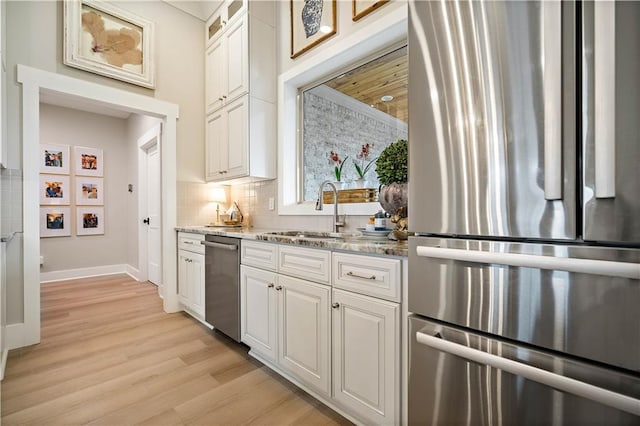 kitchen featuring sink, light hardwood / wood-style floors, light stone counters, white cabinetry, and stainless steel appliances