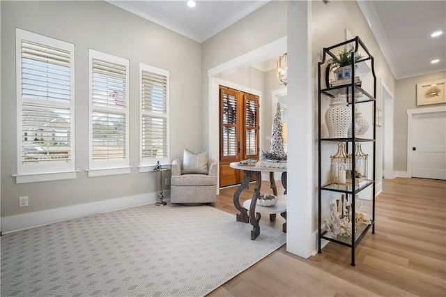 living area with crown molding, an inviting chandelier, and light wood-type flooring