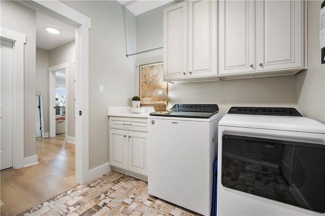 washroom with washer and dryer, cabinets, and light hardwood / wood-style flooring