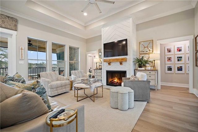 living room with ceiling fan, light hardwood / wood-style floors, crown molding, and a fireplace