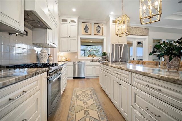 kitchen with white cabinetry, light stone countertops, wall chimney exhaust hood, premium appliances, and decorative light fixtures