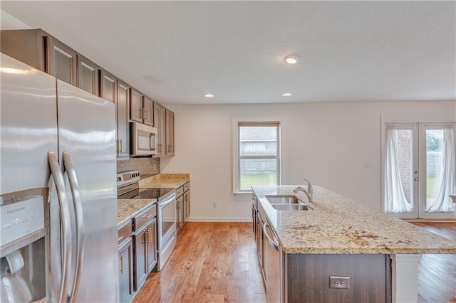 3473 Summer Woods Cir W, Mobile, AL 36695 - kitchen with stainless steel appliances, a sink, light wood-style flooring, an island with sink, and light stone countertops
