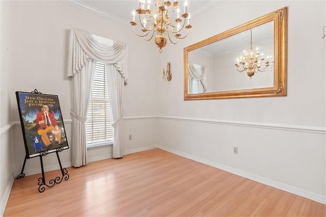 unfurnished room with ornamental molding, wood finished floors, baseboards, and a chandelier