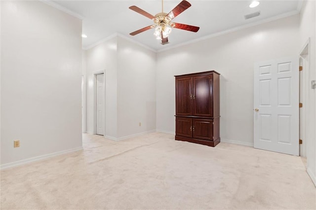 empty room featuring ornamental molding, baseboards, visible vents, and light carpet