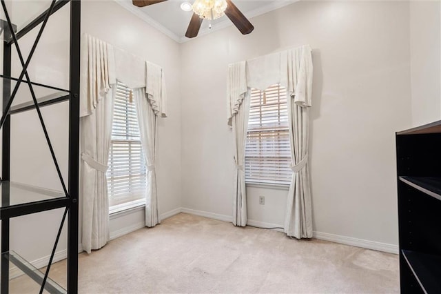 interior space with ceiling fan, baseboards, ornamental molding, and carpet flooring