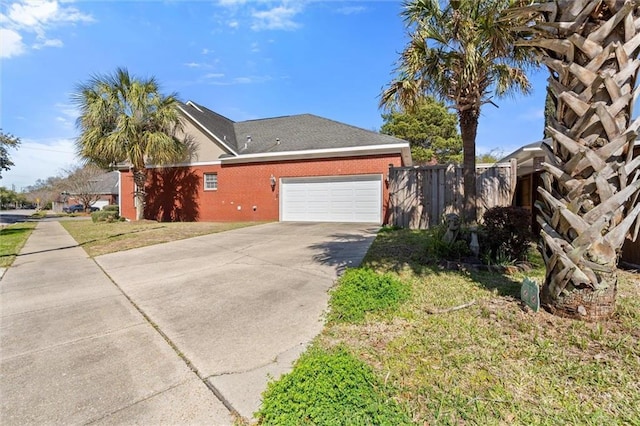 view of home's exterior with a lawn, driveway, fence, a garage, and brick siding